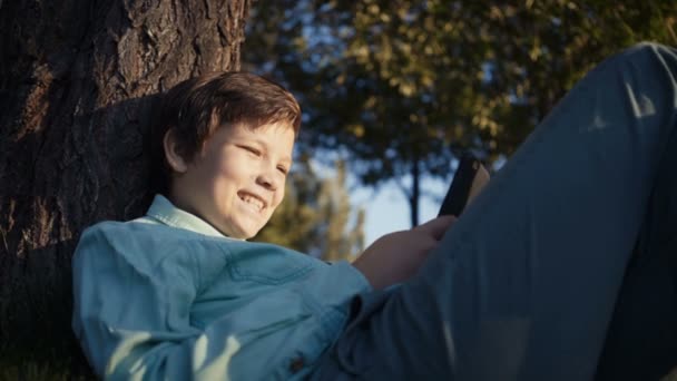 Adolescent jouer à des jeux vidéo sur son smartphone à l'extérieur . — Video