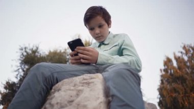 Onun smartphone açık havada üzerinde video oyunları oynarken genç.