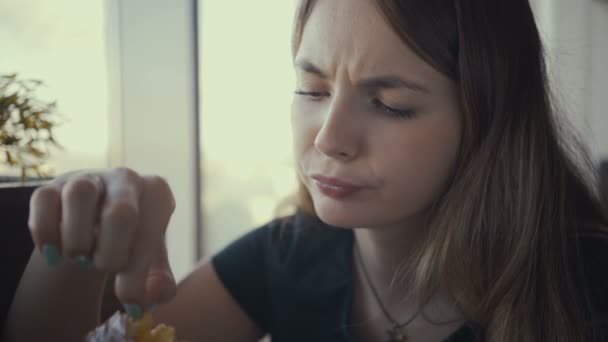 Jonge vrouw beeldmateriaal eten smakelijke hamburger in fast-food restaurant. — Stockvideo