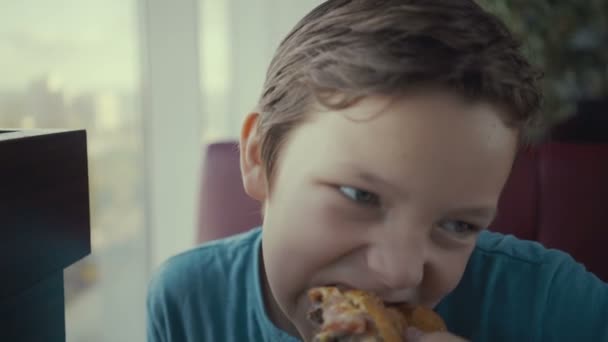 Filmagem feliz jovem adolescente comendo hambúrguer saboroso no restaurante fast food . — Vídeo de Stock