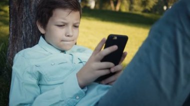Onun smartphone açık havada üzerinde video oyunları oynarken genç.