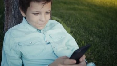 Onun smartphone açık havada üzerinde video oyunları oynarken genç.