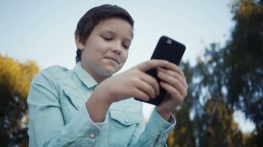 Onun smartphone açık havada üzerinde video oyunları oynarken genç.