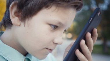Onun smartphone açık havada üzerinde video oyunları oynarken genç.
