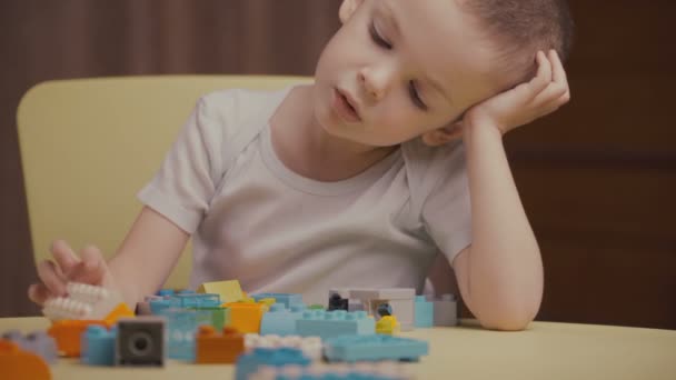 Filmati piccolo ragazzo felice che gioca con blocchi colorati di un costruttore a casa — Video Stock