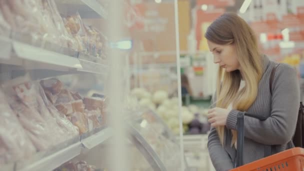 Frau im Supermarkt wählt Fleisch. — Stockvideo
