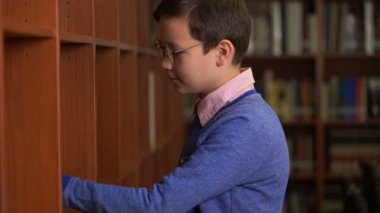 sevimli öğrenci bir kitap okuma için kitaplığa seçer.