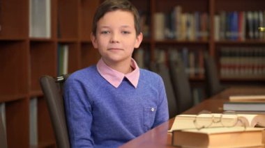 Kütüphane içinde bookshelf yakınındaki sevimli okul portre çekim oturur