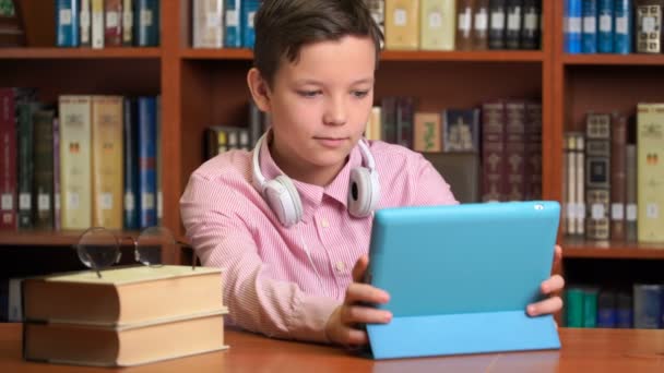 Schattig schooljongen met behulp van computer, tablet en luisteren naar het College. — Stockvideo