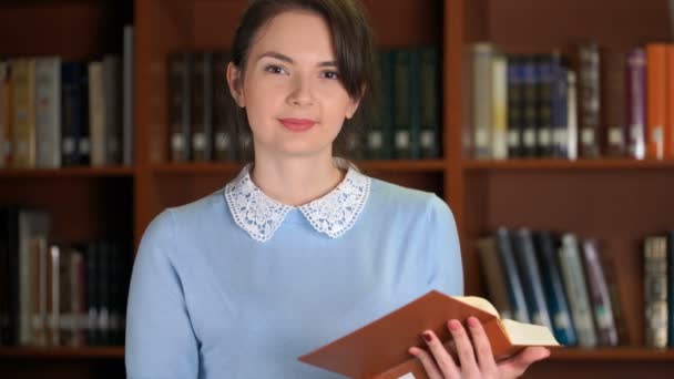 Portret van lachende prachtige mooie vrouw met boek in bibliotheek office boekenplank achtergrond — Stockvideo