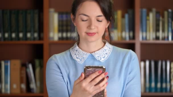 Portret van stijlvolle mooie zakenvrouw glimlachend gebruikend smartphone voor SMS bericht of social media app in bibliotheek kantoor browsen. — Stockvideo