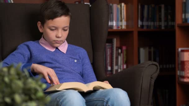 Porträtt av skolpojke gör sina läxor i bibliotek eller rum. — Stockvideo