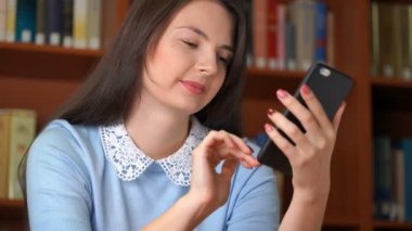 Şık güzel iş kadını gülümseyen portresi görüntüleri için manifatura mesaj smartphone kullanarak veya sosyal medya uygulaması kitaplığı Office tarama. 4 k modern video