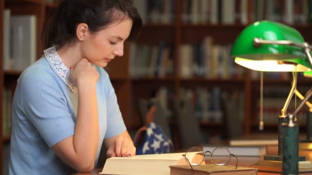 Красотка читает книги в библиотеке — стоковое видео