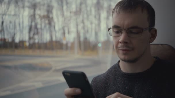 Jeune homme utilisant un smartphone pendant le trajet en bus — Video