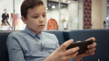 sevimli çocuk köstebek salonda kanepede oturur ve duygusal bir oyunda onun smartphone üzerinde çalış