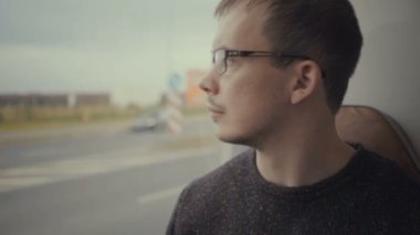 Genç adam otobüs yolculuğu sırasında pencereden dışarı bakarak