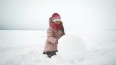 Kız Kışın kardan adam için büyük kar topu rulo.