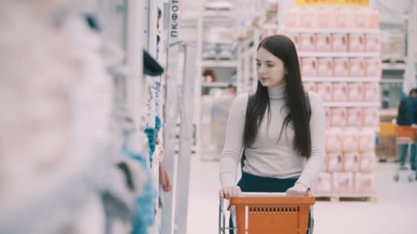 Mujer joven elige toallas en el supermercado — Vídeo de stock
