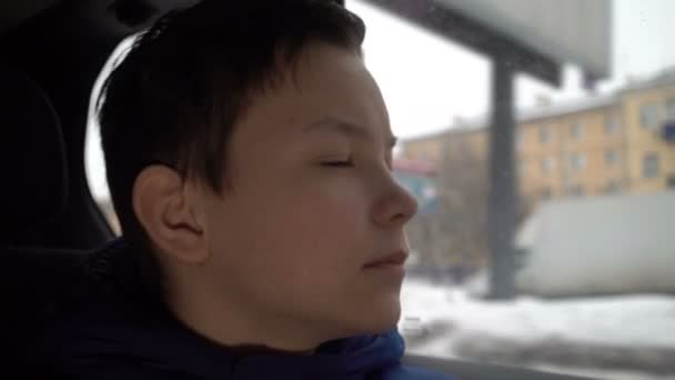 Έφηβος κοιτάζει έξω από το παράθυρο του αυτοκινήτου το χειμώνα — Αρχείο Βίντεο