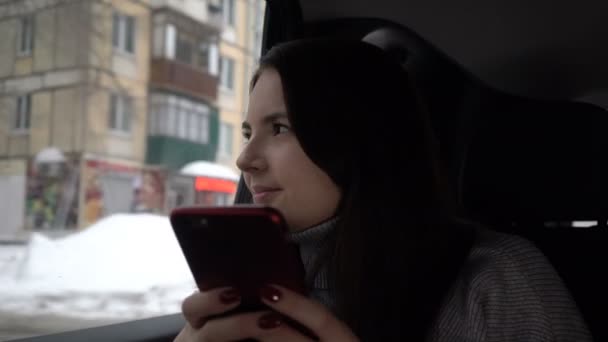 Jonge vrouw met behulp van de smartphone tijdens de taxirit in stad — Stockvideo