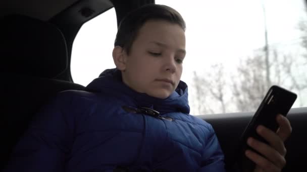 Niño usando smartphone durante un viaje en taxi por la ciudad — Vídeos de Stock