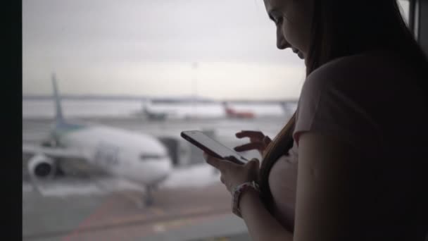 Frau benutzt Handy am Flughafen-Terminal und wartet auf das Einsteigen — Stockvideo