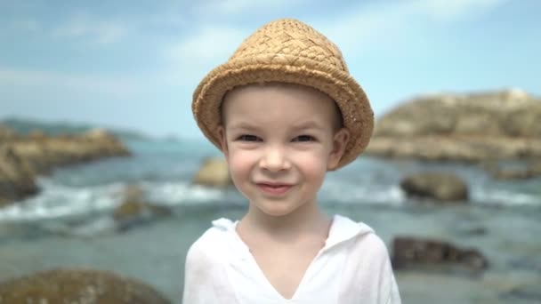Porträt süßer Junge mit Strohhut am Strand — Stockvideo