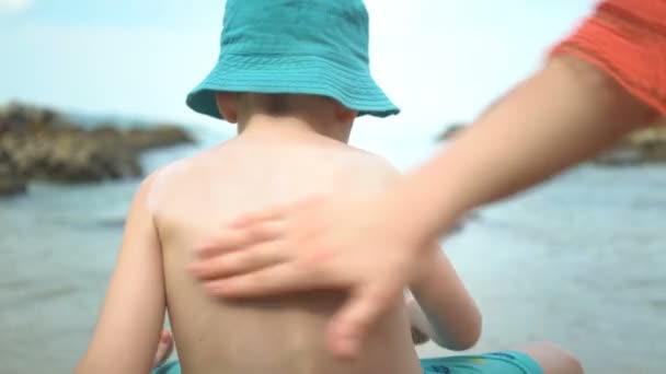 Moeder het toepassen van sunblock Cream op Son terug op het strand. — Stockvideo