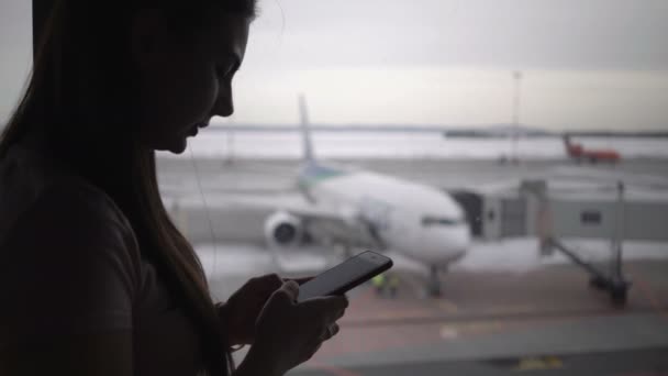 Γυναίκα που χρησιμοποιεί κινητό τηλέφωνο στο τερματικό του αεροδρομίου και περιμένει για επιβίβαση στο αεροπλάνο — Αρχείο Βίντεο