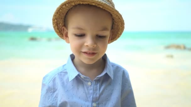 Πορτραίτο χαριτωμένο αγόρι με ένα ψάθινο καπέλο στην παραλία. — Αρχείο Βίντεο