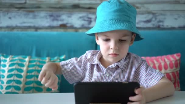 카페에 앉아 스마트폰을 사용 하는 귀여운 소년. — 비디오