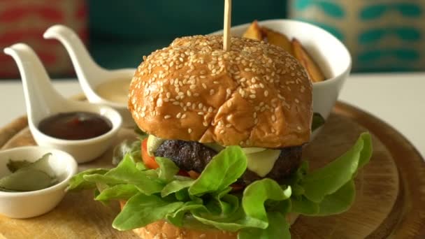 Gire la hamburguesa casera con papas fritas y salsas en una bandeja de madera — Vídeos de Stock