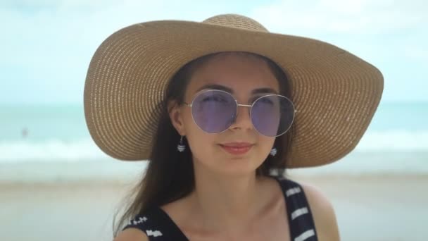 Portret van mooie jonge vrouw met hoed en zonnebril op het strand — Stockvideo