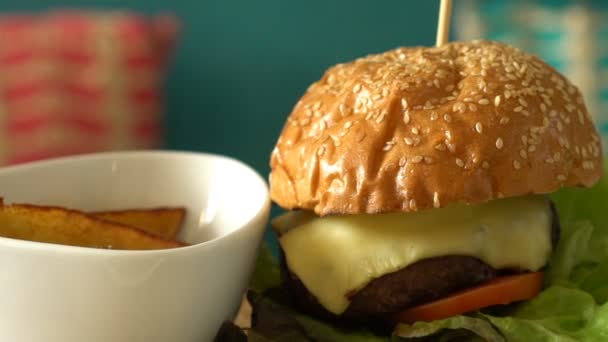 Faire pivoter un hamburger maison avec des pommes de terre frites et des sauces sur un plateau en bois — Video