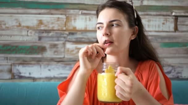 Joven mezquina bebiendo batido de mango tropical fresco — Vídeos de Stock