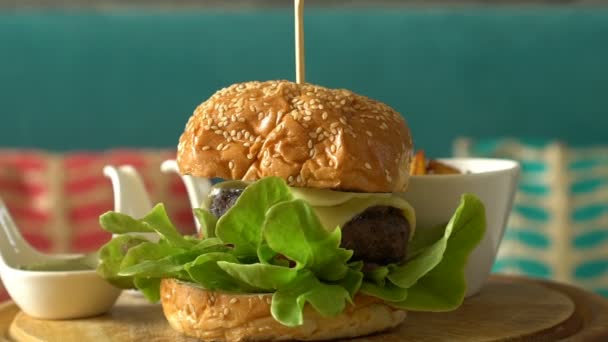 Поворот домашнего гамбургера с жареной картошкой и соусами на деревянном подносе — стоковое видео
