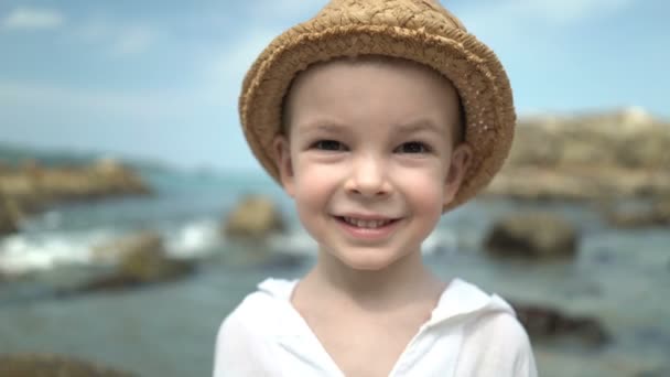 Retrato lindo chico en un sombrero de paja en la playa — Vídeos de Stock