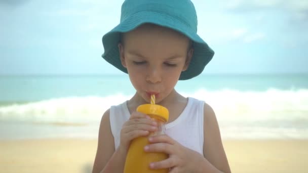 Niedlichen kleinen Jungen trinken frischen tropischen Mango Smoothie Shake am Strand. Sommerzeit-Konzept. — Stockvideo