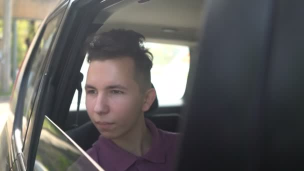 Portret van jonge knappe tiener reizen in een taxi auto met een chauffeur in zonnige dag. — Stockvideo