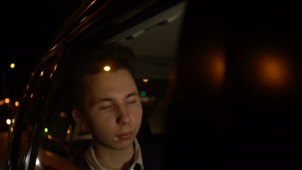 Retrato de un adolescente guapo viajando en un taxi con un conductor en la ciudad nocturna. Imágenes de 4k — Vídeo de stock