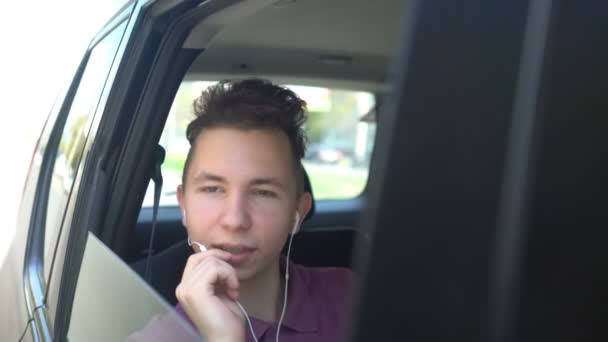 Lachende tiener telefoneren tijdens het zitten op de achterbank van een auto — Stockvideo