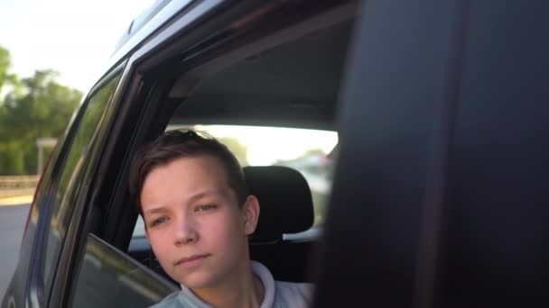 Portrait de jeune adolescent beau voyageant dans une voiture de taxi avec un chauffeur dans la journée ensoleillée . — Video