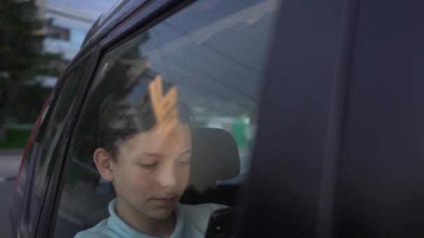 Tiener met behulp van app op zijn telefoon in de avond op achterbank van de auto — Stockvideo