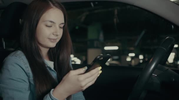 Donna utilizza un'applicazione sul suo telefono mentre seduto in macchina nel parcheggio — Video Stock