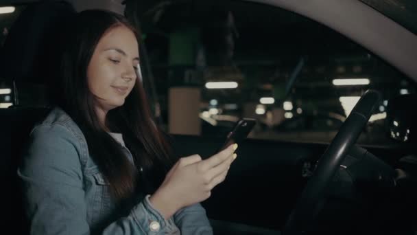 Woman uses an application on his phone while sitting in the car in the parking lot — Stock Video