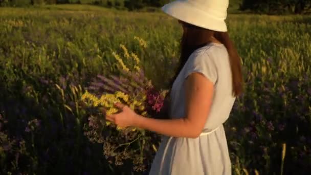 Jovem mulher caminhando com buquê de flores de campo — Vídeo de Stock