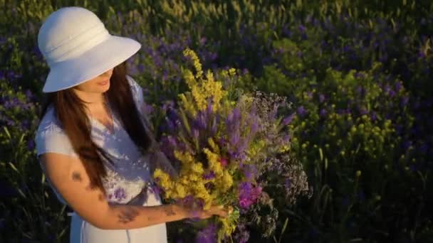 Tarla Çiçeklerinden Buket ile Yürüyen Genç Kadın. — Stok video