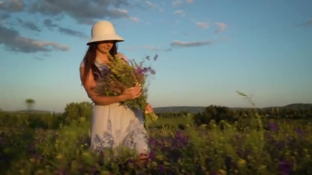Tarla Çiçeklerinden Buket ile Yürüyen Genç Kadın. — Stok video