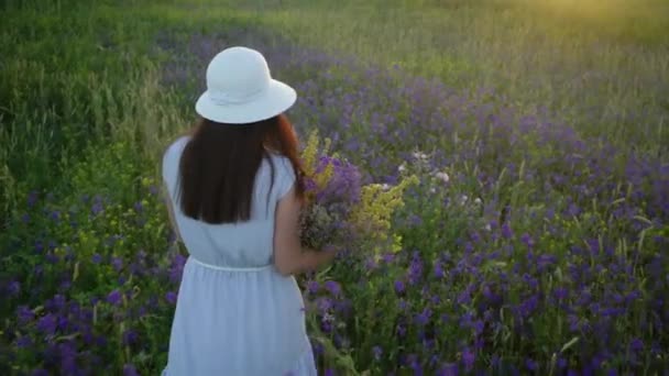 Ung kvinna som går med bukett av fält blommor. — Stockvideo